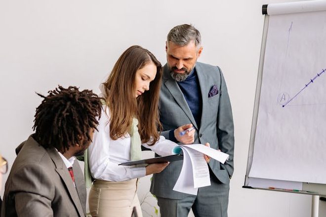 A diverse team collaborating in a modern office with laptops and a whiteboard.